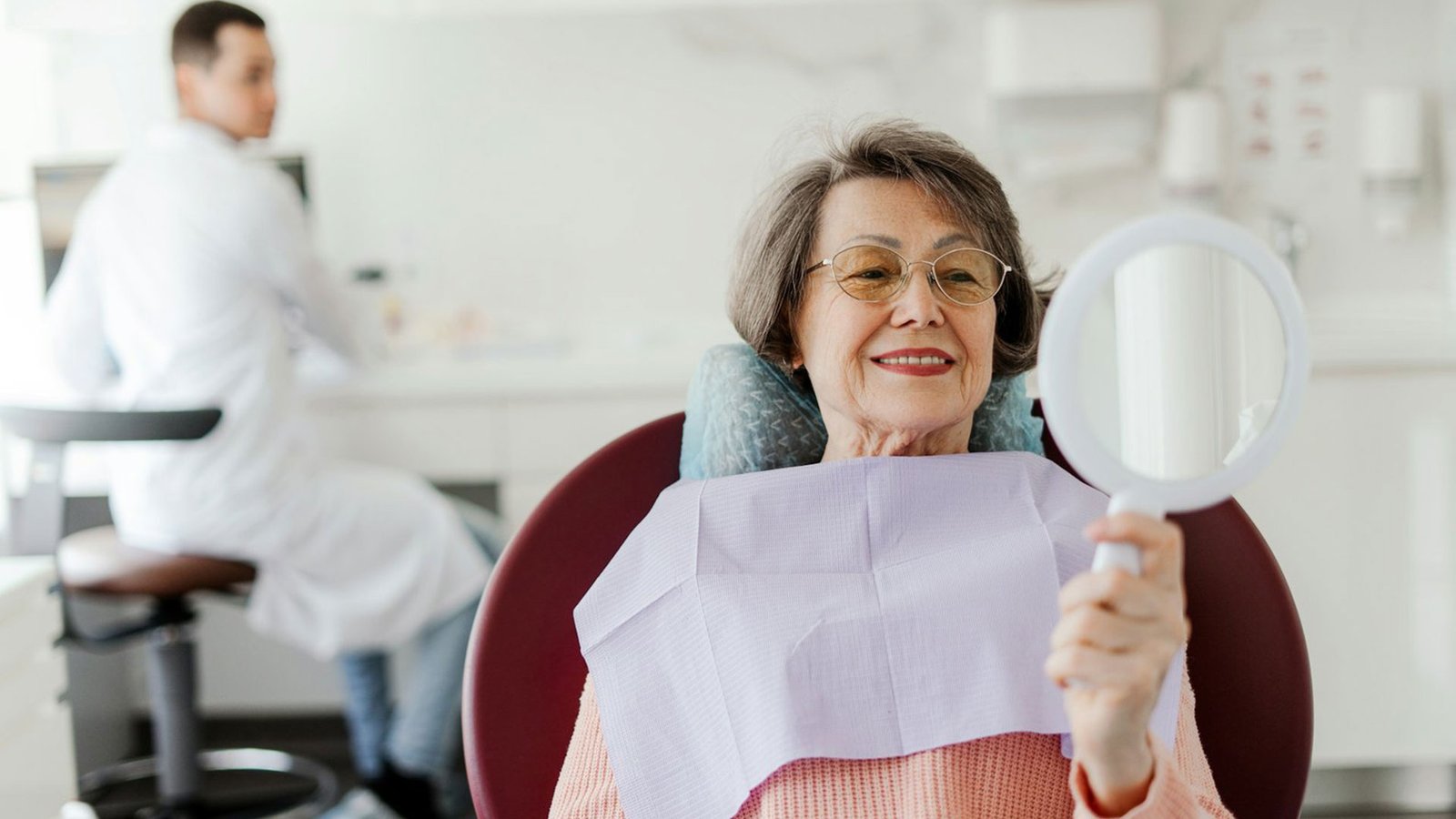 Patient, senior, mature woman holding mirror, looking, talking to senior professional dentist